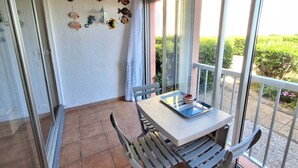 Un balcon agrémenté d’une table, de chaises et d’une décoration murale représentant des poissons.