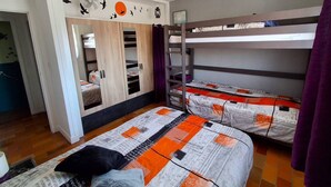 Une chambre avec des lits superposés, une armoire et un ventilateur de plafond.