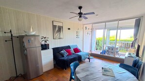 Un espace de vie compact comprenant un coin cuisine, une table à manger, un canapé et un balcon avec vue.