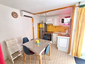 Cocina compacta con mesa, sillas, refrigerador y microondas.