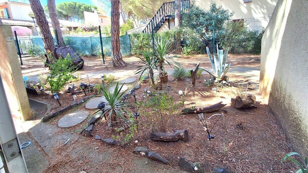 A garden with trees, a stone pathway, and a fence. - APPARTEMENT EN REZ DE JARDIN POUR 4 PERSONNES (LE CAP D AGDE)
