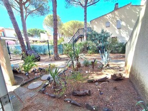 A garden with trees, a stone pathway, and a fence.