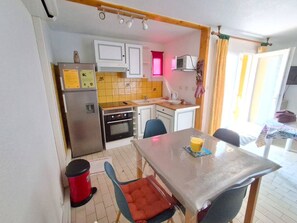 Una cocina compacta equipada con refrigerador, horno, microondas y un pequeño comedor con mesa y sillas.