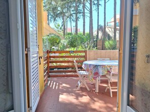 Eine Terrassensitzgruppe mit Tisch und Stühlen, ein Holzzaun und Blick auf Grünflächen und Gebäude.