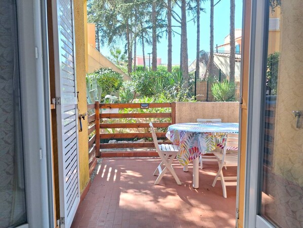Un patio al aire libre con una mesa y sillas, una valla de madera y vistas a zonas verdes y edificios.