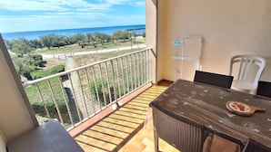 Ein Balkon mit Meerblick, einem Tisch mit Stühlen und einem Wäscheständer.