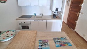 Eine kleine Küche mit weißen Schränken, einer Spüle, einem Herd und einer Kaffeemaschine.