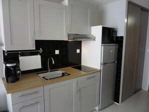 Een koelkast, een microgolfoven, kookgerei, borden en bestek