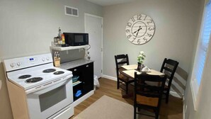 A compact kitchen with a stove, microwave, and a clock on the wall. - Skots Villa Bottom East. Centrally located near Sanford Medical Center & Midco. (Sioux Falls)