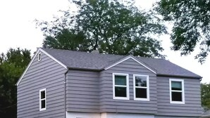 A two-story house with a grey siding exterior, white trim, and a front porch with steps. - Skots Villa Bottom East. Centrally located near Sanford Medical Center & Midco. (Sioux Falls)