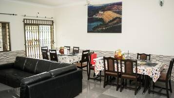 A dining area with a table set for four, a black leather sofa, and a large painting on the wall.