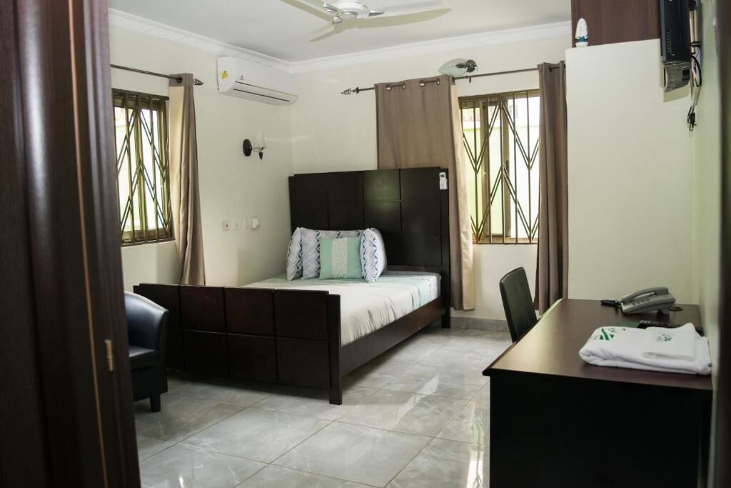 A bedroom with a bed, a desk, a chair, and a ceiling fan.