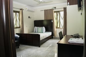 A bedroom with a bed, a desk, a chair, and a ceiling fan. - 3A's Guest House (Akosombo)