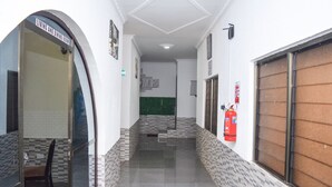 A corridor with a living and dining room sign, a fire extinguisher, and a staircase leading to an upper floor. - 3A's Guest House (Akosombo)