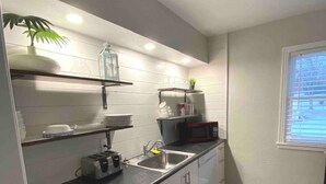 Una cucina moderna con mobili bianchi, un piano di lavoro nero e una finestra con persiane.