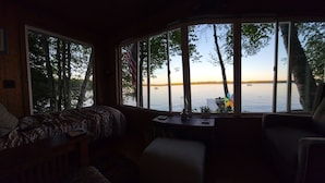 Una baita con una grande finestra vista lago, un letto e un tavolino.