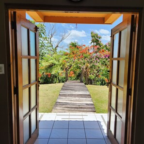 A pathway leading through a wooden door into a garden with a tiled floor. - Casa Campo Obymar, a villa with panoramic views and a private pool. Electric generator (Moca)