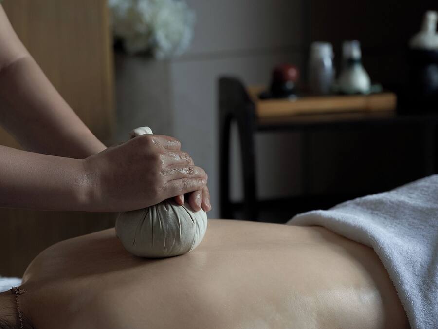 A massage therapy session in progress with a person receiving a massage on their back.