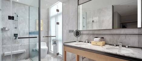Un baño moderno con ducha acristalada, un espejo grande y un lavabo de mármol.