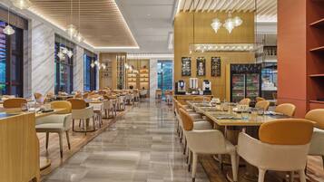 A spacious restaurant with multiple dining tables and chairs, a coffee machine, and a refrigerator.