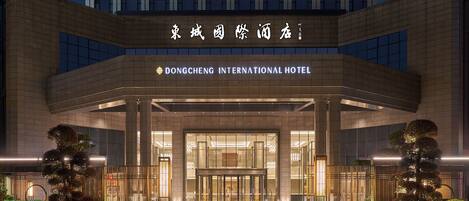 The Dongcheng International Hotel entrance with a modern design, featuring a glass facade and a well-lit entrance area.