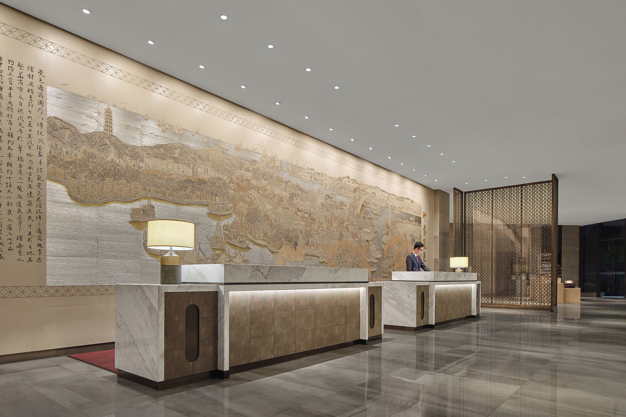 A modern reception area with a large mural, marble counters, and a traditional decorative screen.