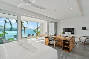 Una habitació d'hotel moderna amb un llit gran, un escriptori i vistes a l'oceà.