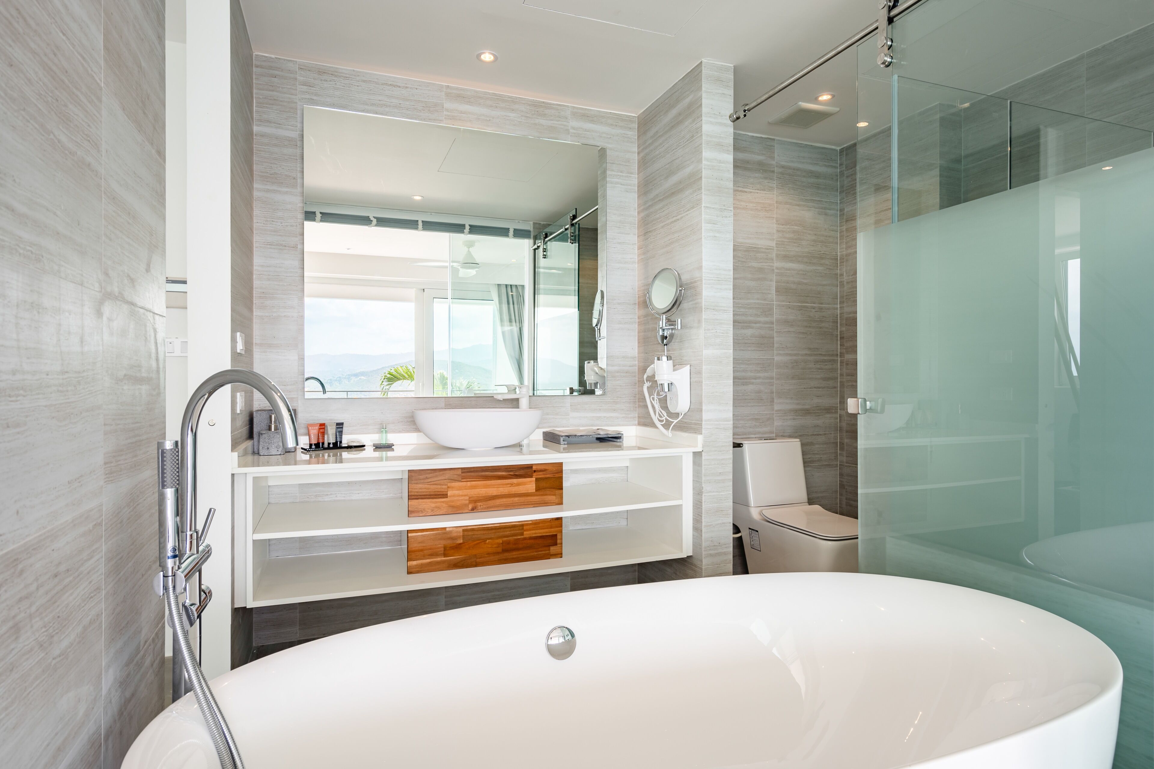 A modern bathroom with a large freestanding bathtub, a glass-enclosed shower, and a vanity with a large mirror and a sink.