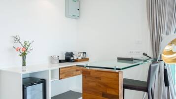 A modern kitchen with a glass countertop, wooden cabinets, a built-in mini-fridge, and a coffee station.