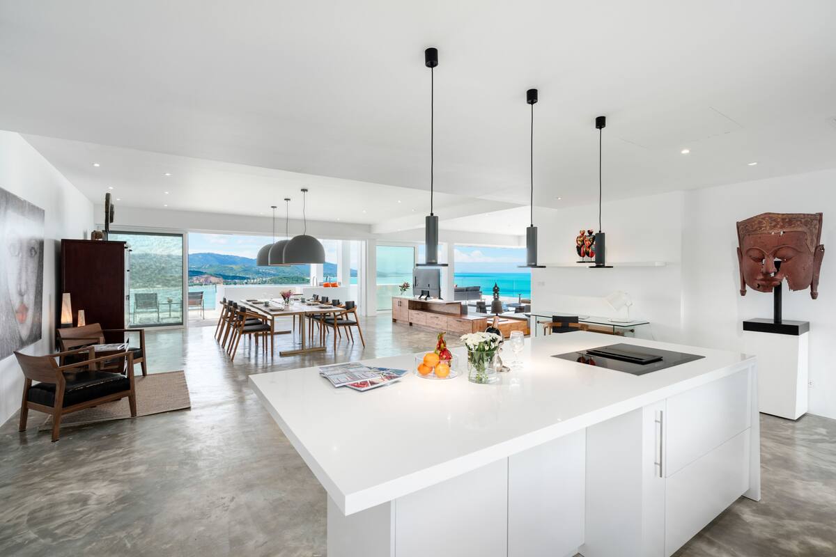 A modern kitchen with a large island, dining area, and a view of the ocean.
