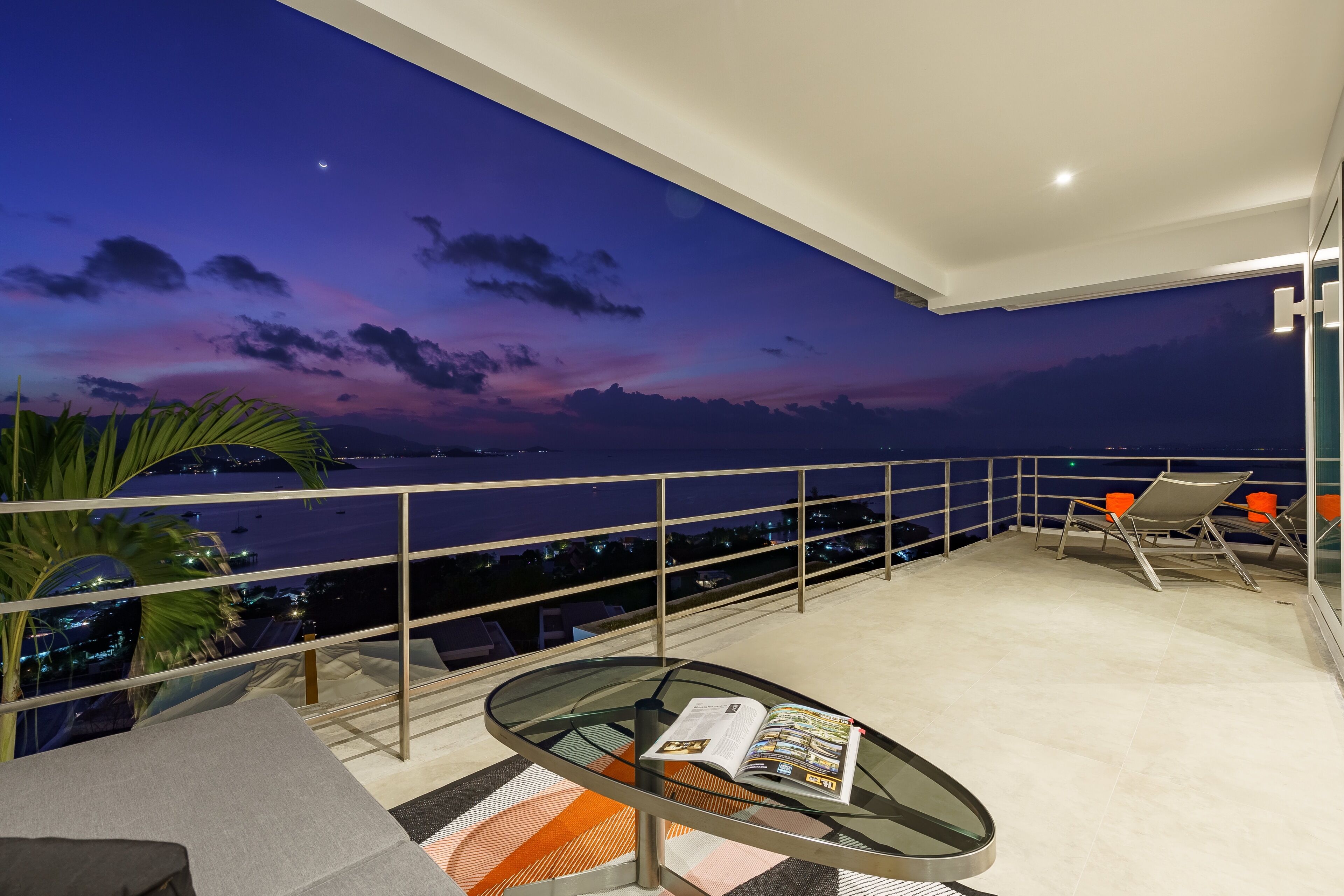 Un balcon avec une table en verre, un magazine et deux chaises.