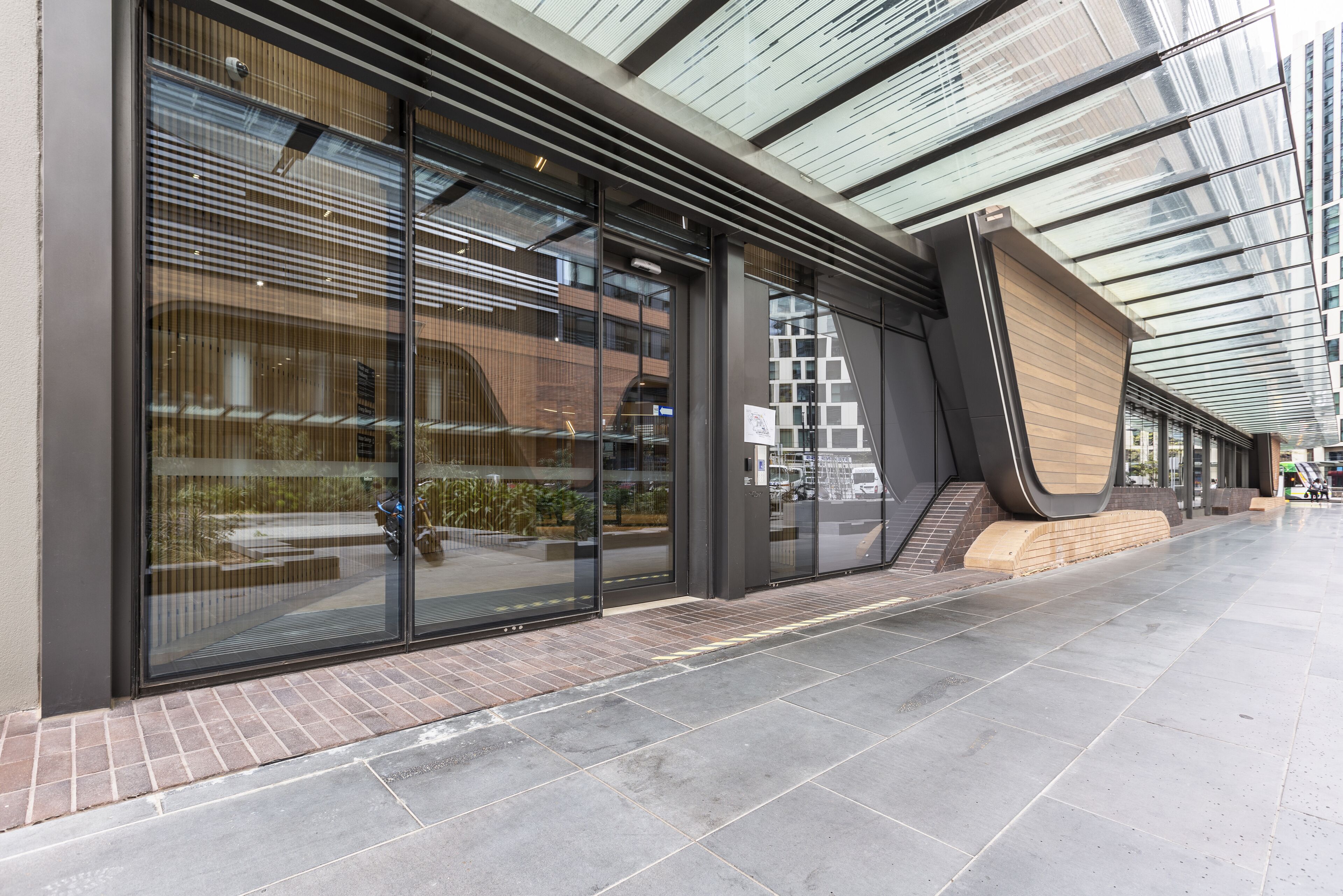 A modern building with large glass windows, a brick base, and a sloped roof structure.