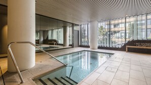 Una piscina interior con paredes de vidrio transparente, un letrero que indica 'no buceo' y un piso de baldosas.