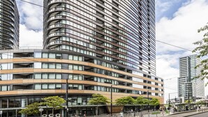 Un edificio moderno de gran altura con fachada curva, varios balcones y exterior de vidrio.