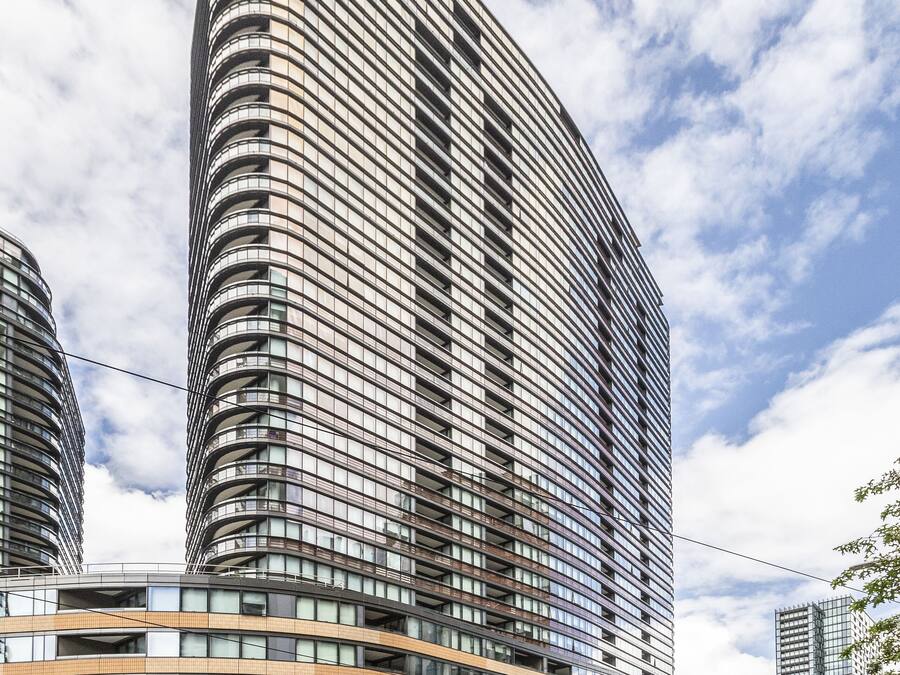 Un edificio moderno de gran altura con fachada curva, varios balcones y exterior de vidrio.