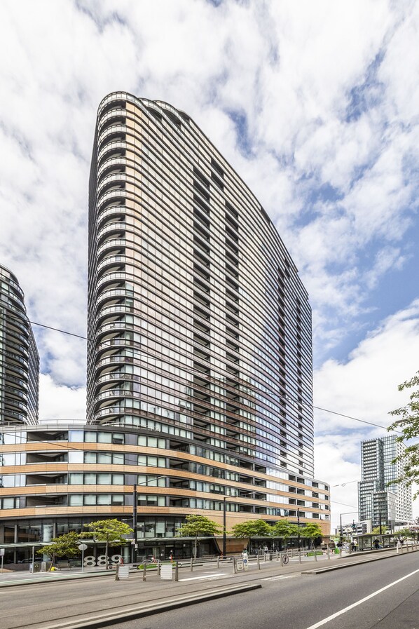Un immeuble moderne de grande hauteur, doté d’une façade incurvée, de nombreux balcons et d’une enveloppe extérieure en verre.