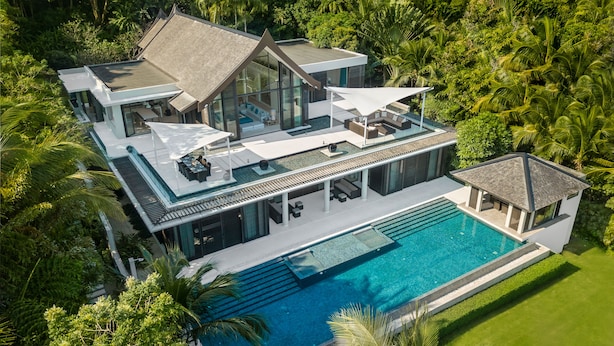 A modern multi-story house with a large swimming pool, surrounded by lush greenery. - Villa Vikasa (Pa Klok)