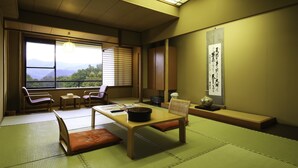 Een traditionele Japanse kamer met tatami vloerbedekking, een lage tafel en uitzicht op bergen door het raam.