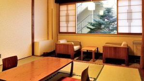Een traditionele Japanse kamer met tatami vloeren, een houten tafel en zitplaatsen op laag niveau.