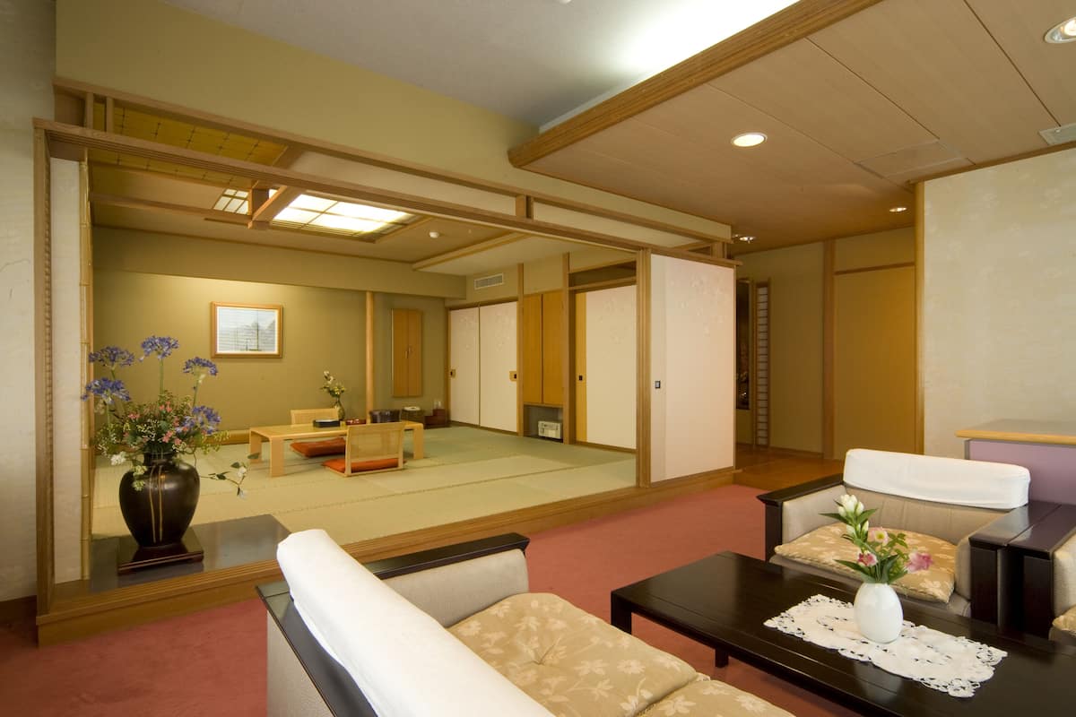 A traditional Japanese room with tatami flooring, a low wooden table, a sofa, and a tatami mat-covered floor.