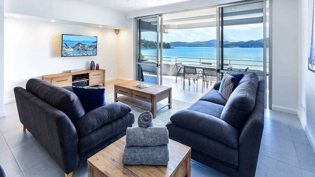 A modern living room with a sofa set, a coffee table, and a TV on the wall.