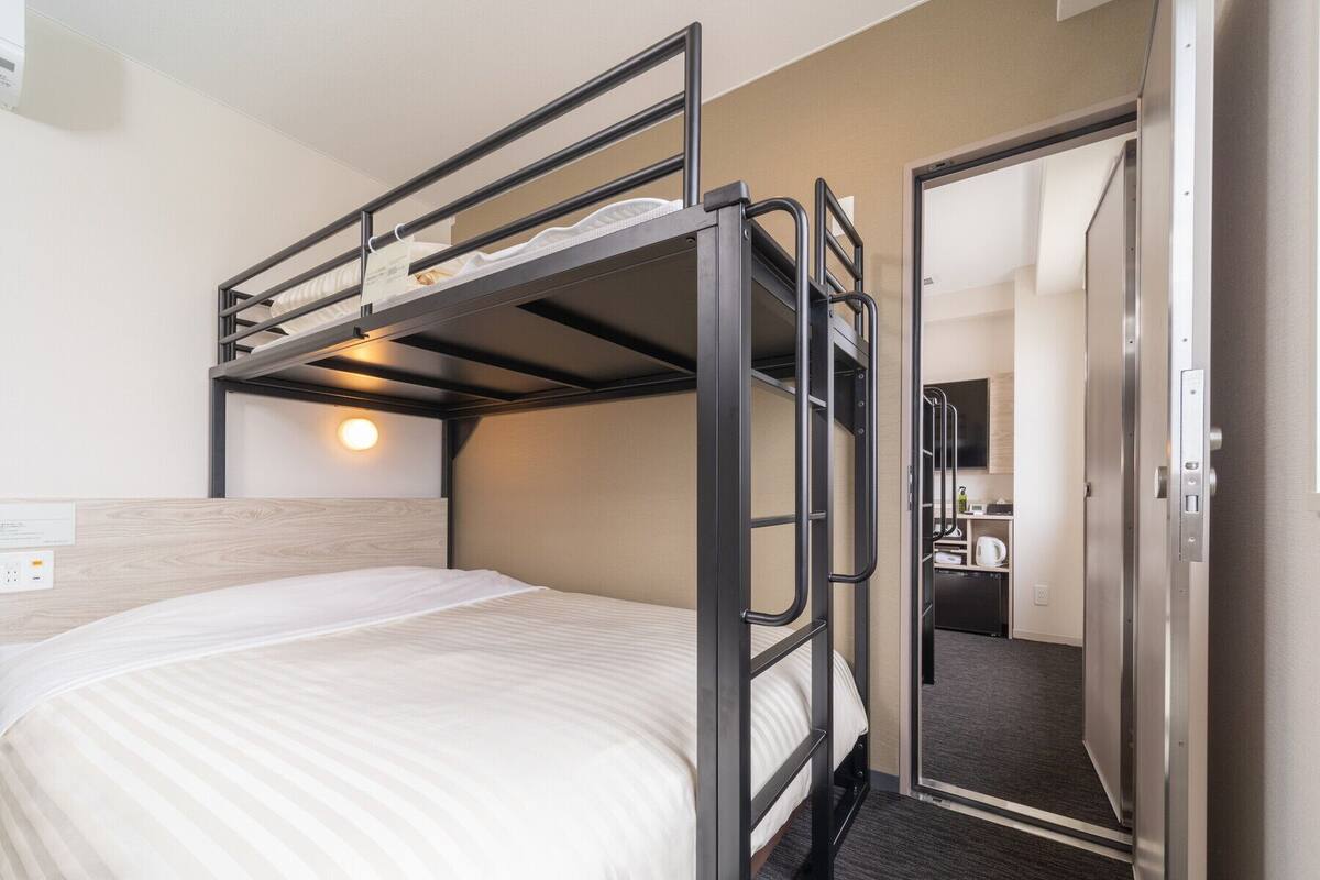 A bunk bed room with a headboard, a bedside table, and a mirror.