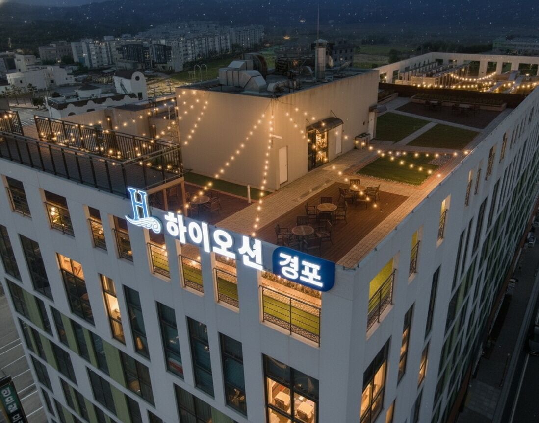 A hotel rooftop with string lights, outdoor seating, and a sign in Korean.