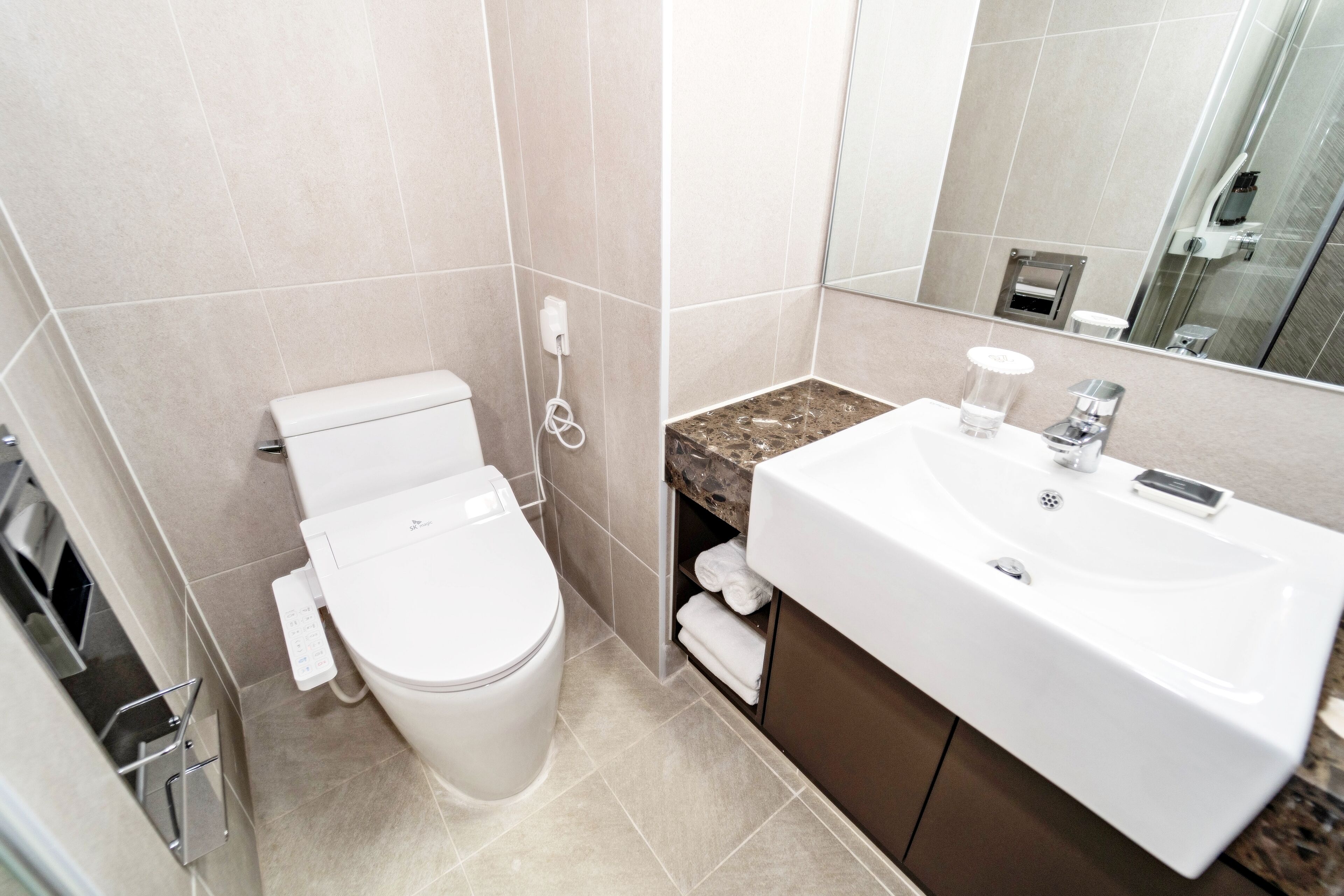 A modern bathroom with a toilet, sink, and mirror.