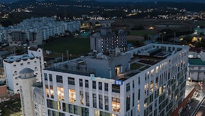 A modern building with multiple floors and a flat roof, surrounded by other buildings and a clear night sky. - Hi Ocean Hotel Gyeongpo (Gangneung)