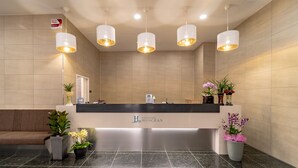 A reception area with a modern design, featuring a reception desk, multiple hanging pendant lights, and potted plants. - Hi Ocean Hotel Gyeongpo (Gangneung)