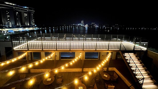 A rooftop bar with string lights, outdoor seating, and a view of the city at night. - Hi Ocean Hotel Gyeongpo (Gangneung)