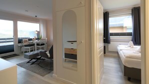 A modern hotel room with a dining area, a large wardrobe, and a bed with a view. - Apartment Widlak - Beach crossing K.Christiansen (Sylt)