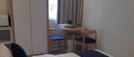 A hotel room with two beds, a desk, a chair, and a window with curtains.