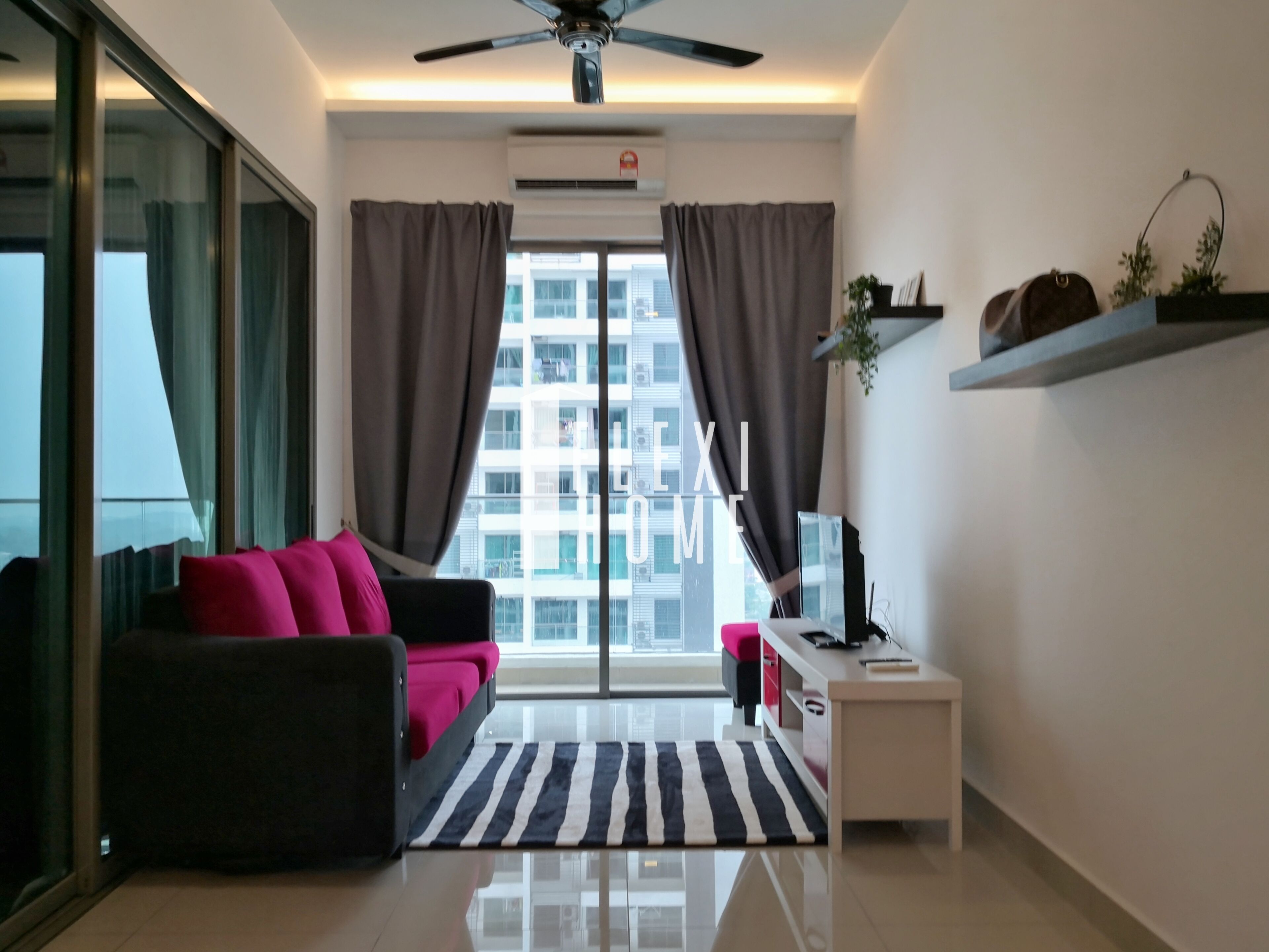 A modern living room with a sofa, a TV, a small table, and a window with curtains.